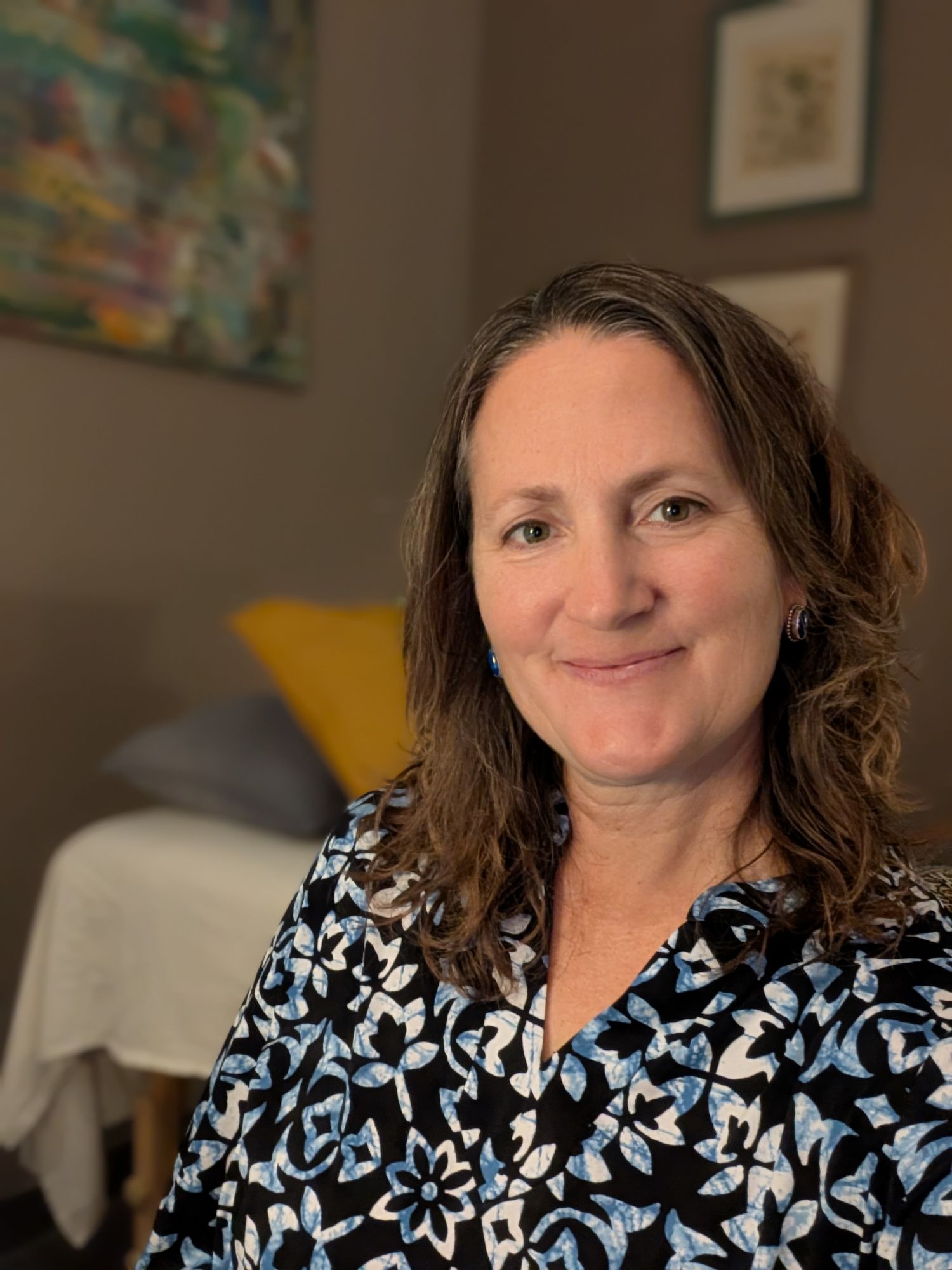 brown haired woman in reiki studio with beige walls and therapy bed